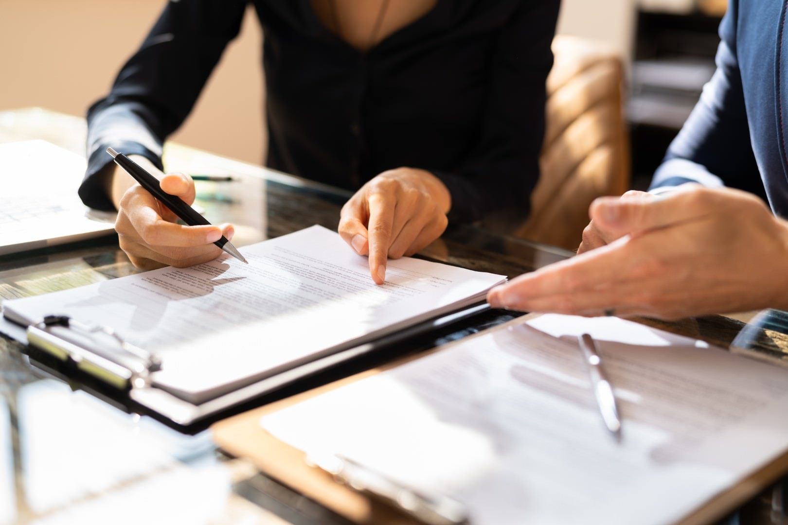 Two people reviewing a contract page by page at a conference table